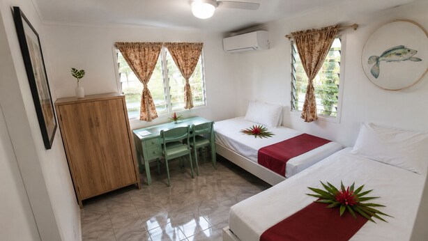 Una habitación con dos camas, un escritorio y un armario.