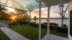 Un espacio al aire libre techado con vistas al mar y al atardecer.