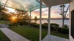 Ein überdachter Außenbereich mit Blick auf das Meer und den Sonnenuntergang.