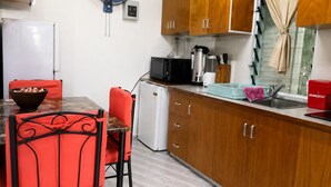 Una cocina compacta con una mesa de comedor, sillas, un refrigerador, un microondas y un lavamanos.