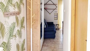 Un couloir avec un porte-manteau en bois, un canapé bleu et un calendrier mural.