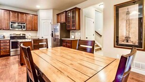 A modern kitchen with wooden cabinets, stainless steel appliances, and a dining area with a wooden table and chairs. - The Haven @ Justice Wine~HotTub~Game Room (Colorado Springs)
