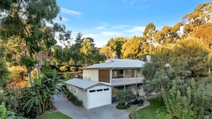 A two-story house with a garage, surrounded by lush greenery and trees. - Resort Style Apartment Escape with Heated Pool, Tennis Court Outdoor BBQ (Bellevue Heights)