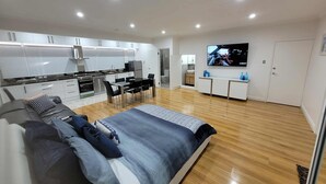 A modern apartment with a large bed, a dining area, a kitchen, and a TV in the living room. - Resort Style Apartment Escape with Heated Pool, Tennis Court Outdoor BBQ (Bellevue Heights)