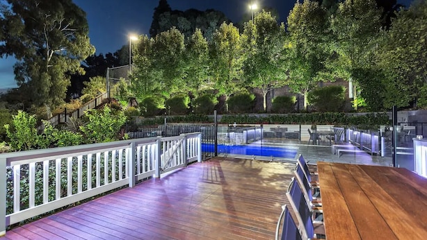An outdoor deck with a wooden floor, metal railing, and seating area. - Resort Style Apartment Escape with Heated Pool, Tennis Court Outdoor BBQ (Bellevue Heights)