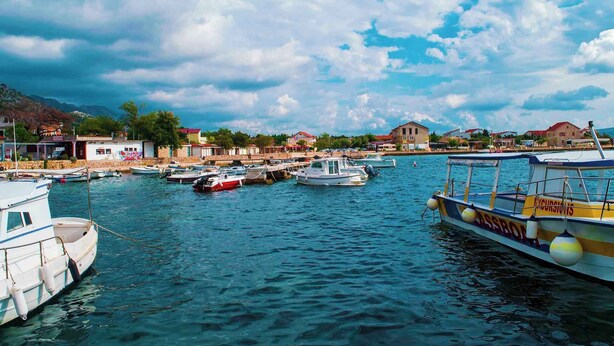A marina with various boats docked, a waterfront building, and a mountainous backdrop. - Holiday apartment Apartment for 3 people with garden views (Starigrad-Paklenica)
