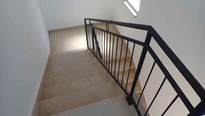 A staircase with a black metal railing, beige steps, and a small window on the right wall. - Holiday apartment Apartment for 3 people with garden views (Starigrad-Paklenica)