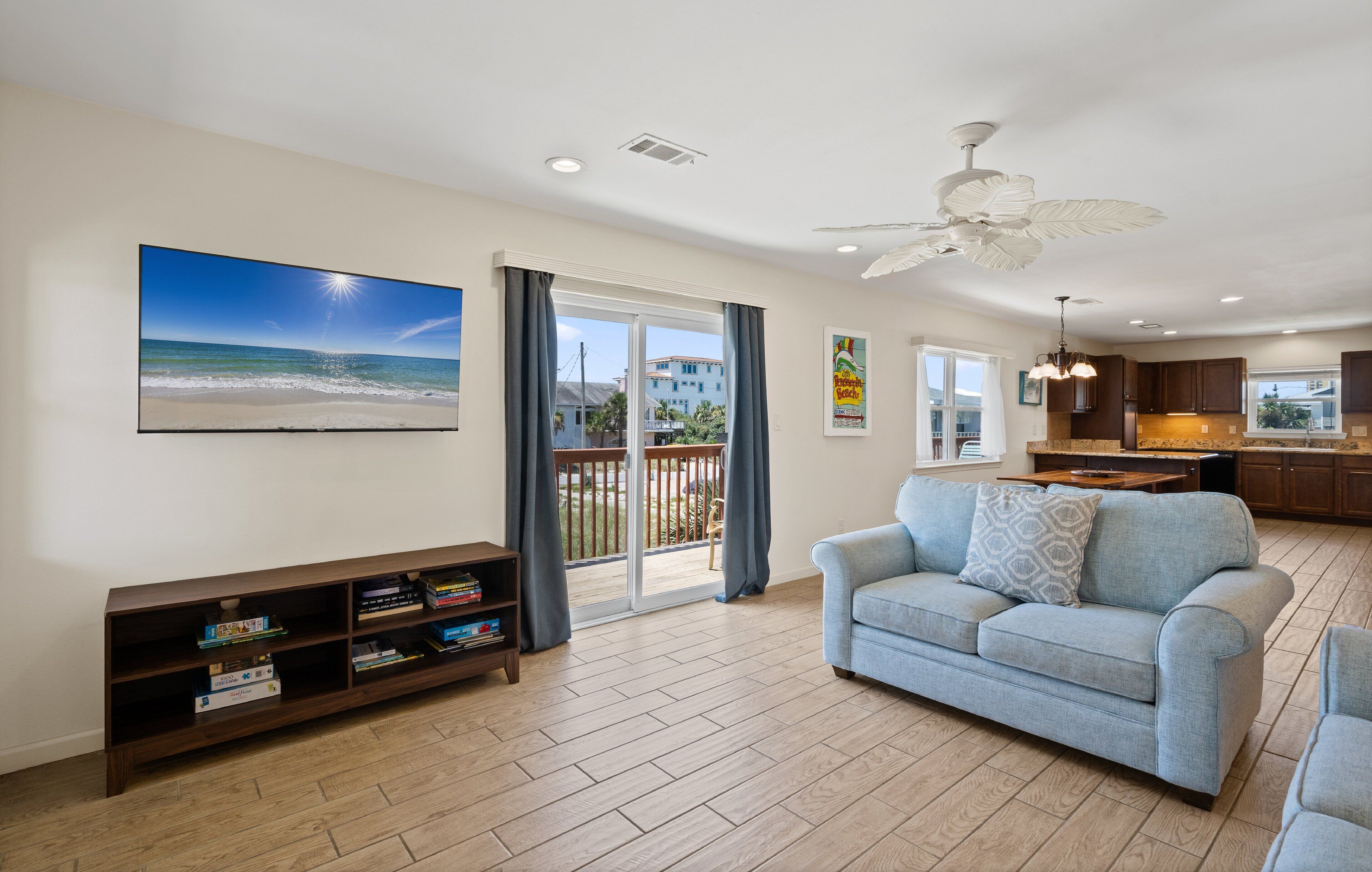 A spacious living room with a large flat-screen TV, a sofa, and a wooden bookshelf.