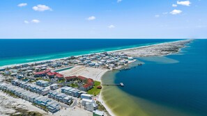 An aerial view of a coastal resort with multiple buildings, a beach, and a pier extending into the ocean.