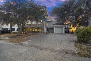 A residential driveway with a paved entrance, surrounded by trees and a garage. - IOP Home, Ocean and Intracoastal Views! Private Pool and widow's walk balcony! (Isle Of Palms)