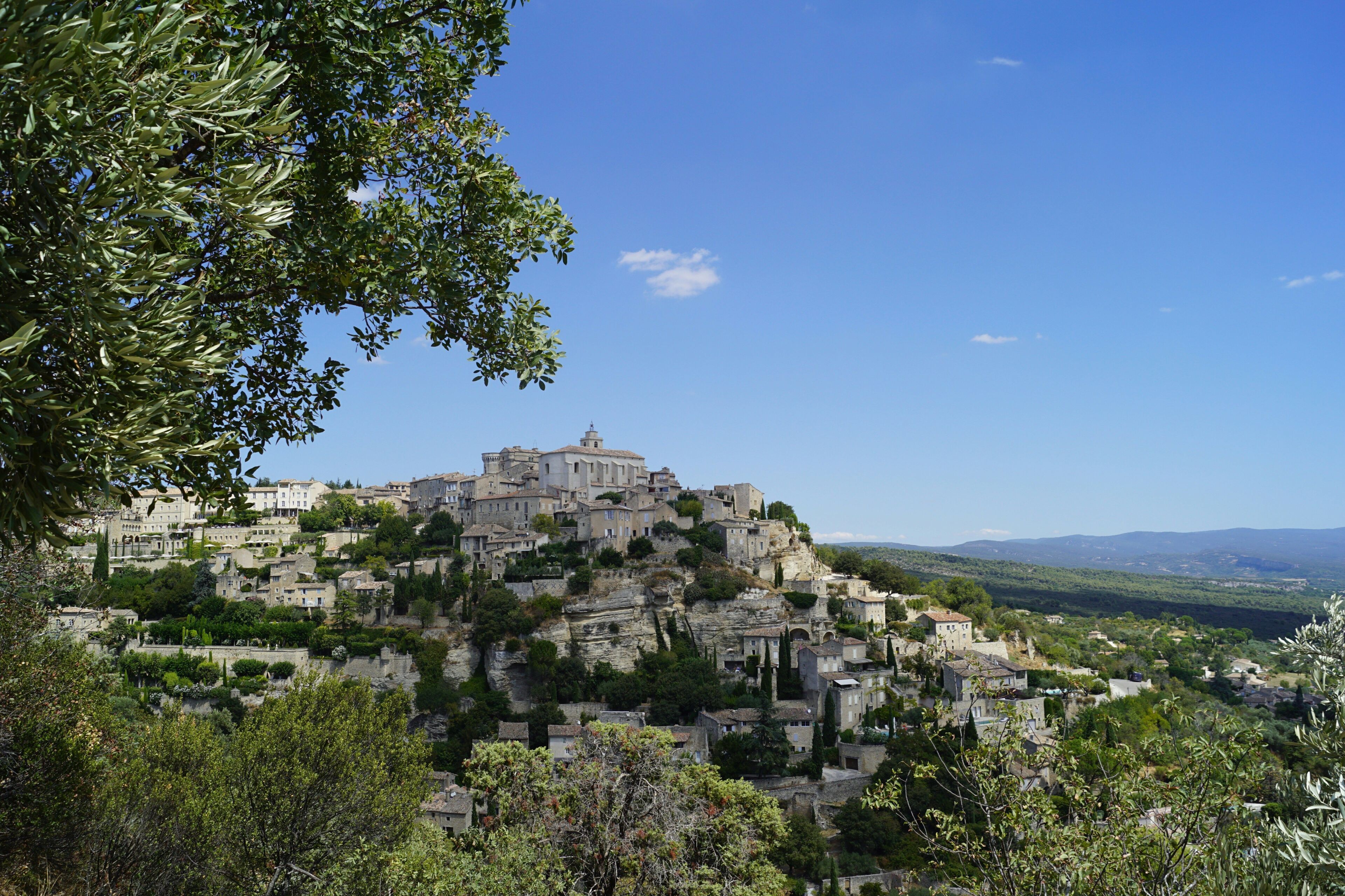 Un pueblo histórico con edificios en una ladera, rodeado de vegetación.
