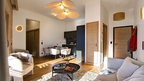 A modern living room with a sofa, a coffee table, and a dining area with chairs and a table. - T3 + Vue sur les pistes | Emplacement privilégié (Alpe d'Huez)