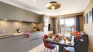 Cocina moderna con gabinetes grises, un comedor con mesa lista para el desayuno y un balcón con vistas.