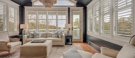 A spacious room with a large window, a sofa, a coffee table, and a lamp.