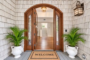 A wooden entrance with a welcome mat, potted plants, and a staircase leading inside. - Luxury Beachfront Home with Guesthouse, Heated Pool & Spa, Putting Green, East Beach Oasis! (Saint Simons Island)