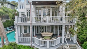 Ein zweistöckiges Haus mit Balkon, Pool und einer Terrasse mit Möbeln.