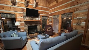 A cozy cabin interior with a stone fireplace, blue sofas, and wooden walls. - Family friendly rustic cabin tucked away, just minutes from entertainment! (Sevierville)