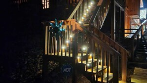 A wooden cabin with a staircase, an American flag, and a sign indicating it is ADA accessible. - Family friendly rustic cabin tucked away, just minutes from entertainment! (Sevierville)