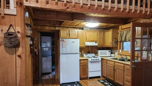 A wooden cabin kitchen with a refrigerator, stove, microwave, and wooden cabinets. - Family friendly rustic cabin tucked away, just minutes from entertainment! (Sevierville)