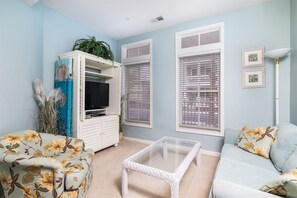 A living room with a sofa, a coffee table, a TV, and a cabinet with a plant.