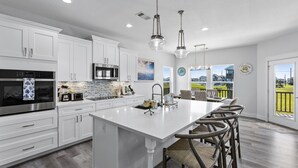 Una cocina moderna con armarios blancos, electrodomésticos de acero inoxidable y una isla grande con taburetes de bar.