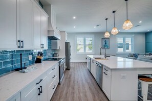 A modern kitchen with white cabinetry, a central island, and pendant lighting. - Endless Summer (Bradenton Beach)