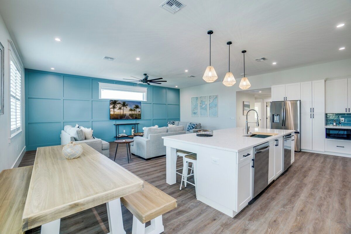 A modern kitchen with a central island, white cabinetry, and pendant lighting.