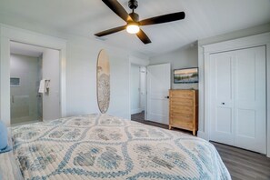 A bedroom with a bed, a ceiling fan, a dresser, and a door. - Endless Summer (Bradenton Beach)