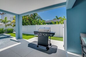 A patio area with a barbecue grill, a small pool, and a view of a residential neighborhood. - Endless Summer (Bradenton Beach)
