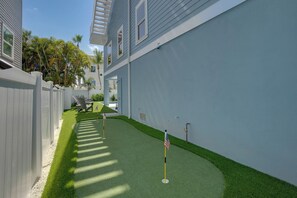 A narrow pathway with artificial grass, a white fence, and a building with a flat roof and windows. - Endless Summer (Bradenton Beach)