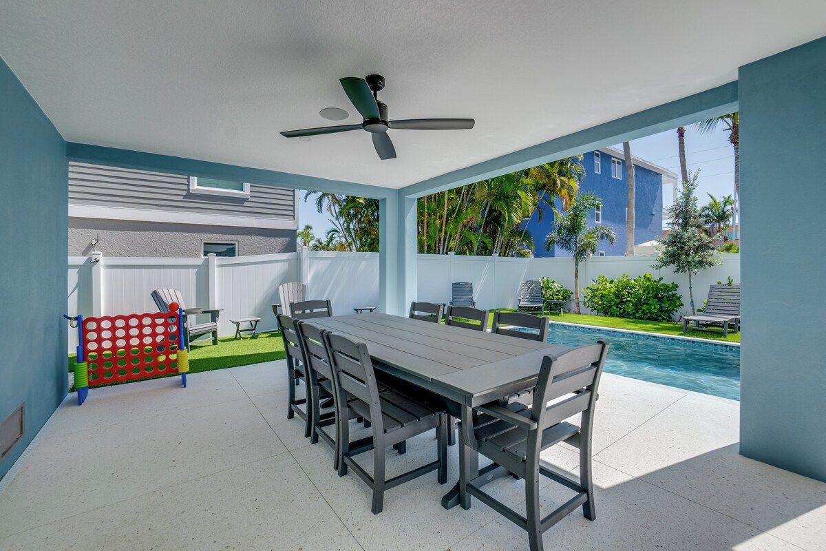 A covered outdoor dining area with a pool view, a ceiling fan, and a red and blue play structure.