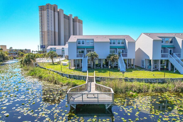 A waterfront property with a dock, a grassy area, and a building with multiple balconies.
