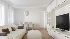 A modern living room with a sofa, ottoman, TV, and white cabinets. - Pure White - My Home in Como (Como)