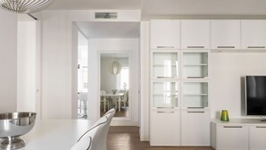 A modern kitchen with white cabinetry, a stainless steel bowl on the counter, and a television on the right. - Pure White - My Home in Como (Como)