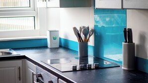 A kitchen with a black countertop, white cabinets, a built-in stove, and a window with blinds. - Private Parking, Urban Comfort & City Haven (Plymouth)