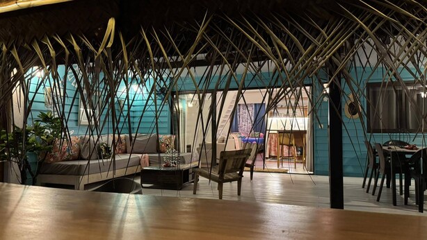 Amplia sala de estar con piso de madera, un conjunto de sofás y una mesa de comedor.
