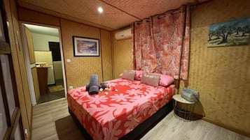 A bedroom with a bed, a nightstand, a painting, and a curtain.