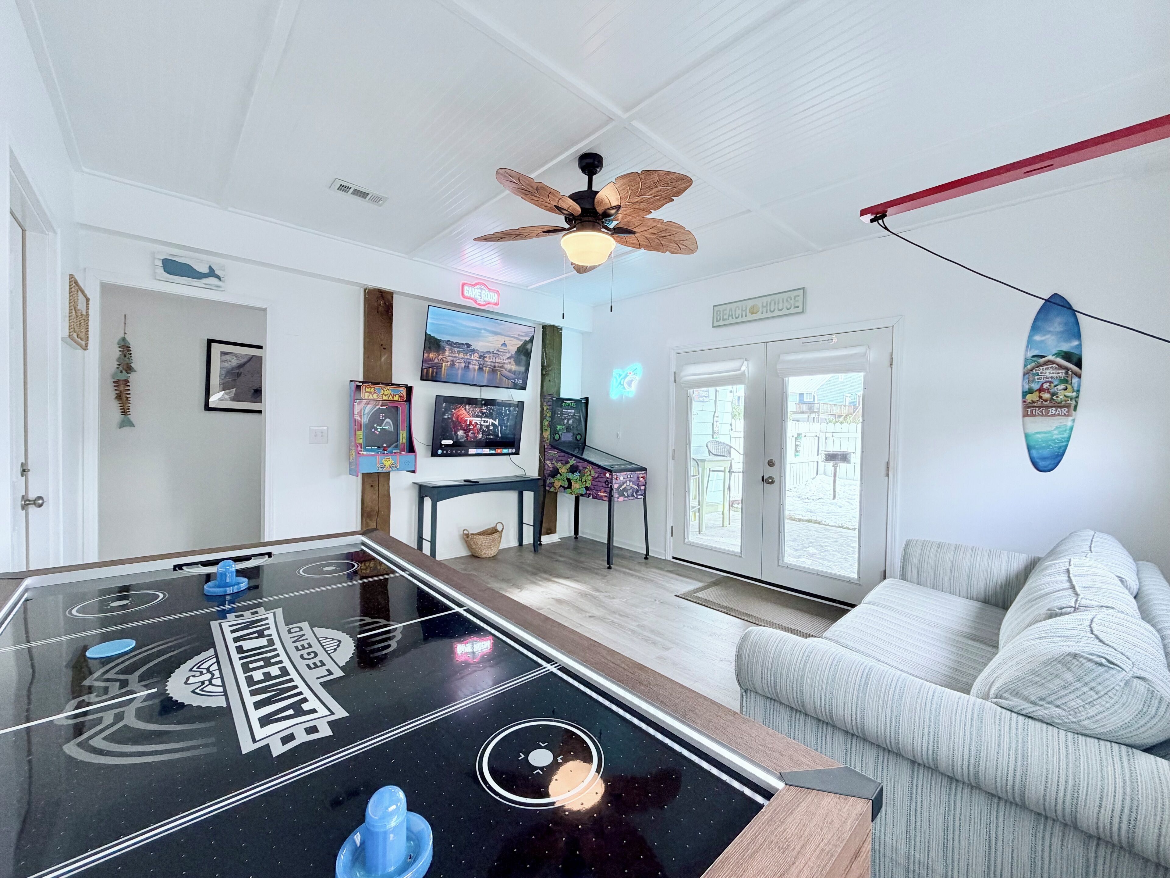 Habitació amb taula de futbolí, sofà, ventilador de sostre i decoració de surf.