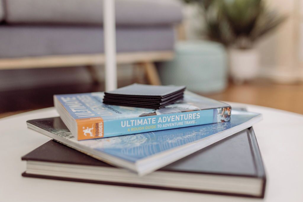 A stack of books titled 'Ultimate Adventures' on a white round table.