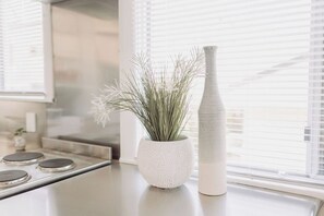 Un comptoir de cuisine sur lequel se trouvent un pot blanc texturé et un grand vase blanc.