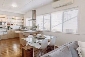Una cocina moderna con una mesa de comedor de vidrio, sillas blancas y una estufa empotrada.