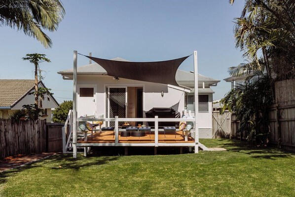 Une maison dotée d’un patio couvert, d’une cour clôturée et d’une terrasse en bois.