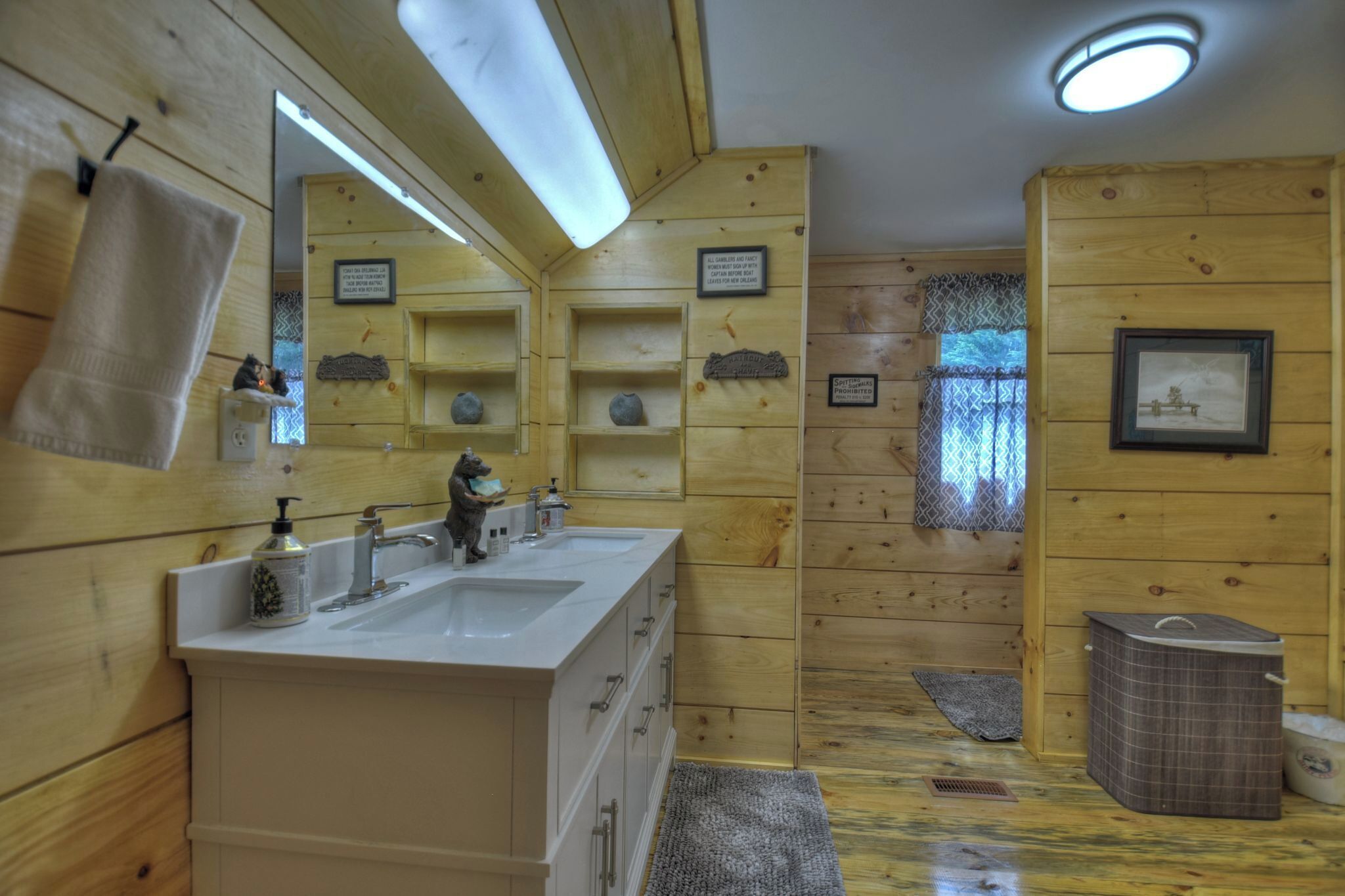 Ein Badezimmer einer Holzhütte mit einem großen Spiegel, zwei Waschbecken, einem Handtuchhalter und einer kleinen Ablagefläche mit Dekoration.