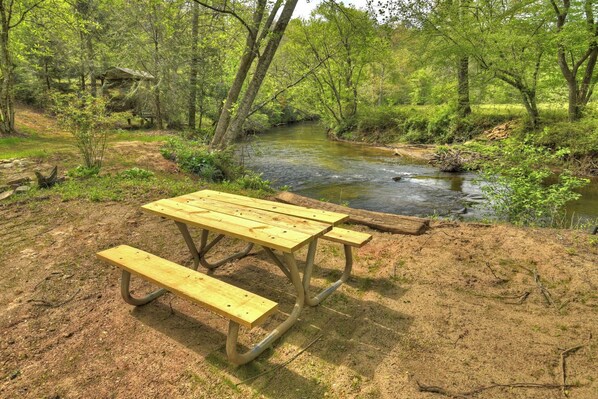 Una mesa de picnic en un área boscosa con un arroyo cerca.