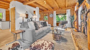 A cozy log cabin interior with a sofa, coffee table, and rustic decor. - Wooded 3BR Luxury Cabin, Close to City & Nature (Greenville)