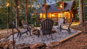 A log cabin with a porch and outdoor seating area. - Wooded 3BR Luxury Cabin, Close to City & Nature (Greenville)