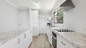 Una cocina moderna con armarios blancos, encimeras de mármol y una campana extractora de acero inoxidable.