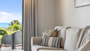 Una sala de estar con un sofá, un sillón y vistas al exterior.