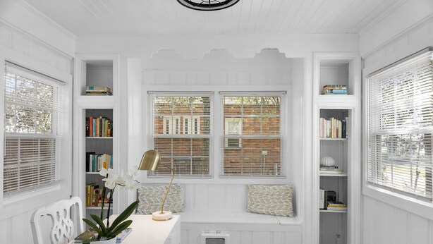 A room with a white interior, a built-in bench with bookshelves, a potted plant, and a radiator. - Forest Hills Manor w/ King Bed (Augusta)