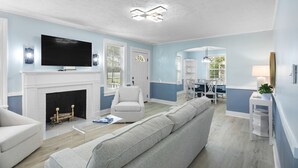 A modern living room with a fireplace, a flat-screen TV, and a comfortable seating area. - Forest Hills Manor w/ King Bed (Augusta)